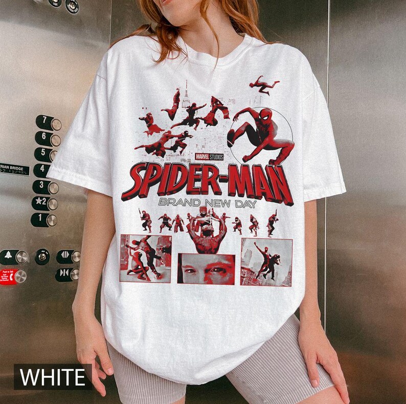 May include: White t-shirt featuring a Spider-Man graphic. The design includes the text "SPIDER-MAN BRAND NEW DAY" in red, along with various action poses of the superhero. The shirt also has the text "WHITE" at the bottom.
