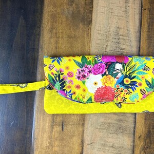 Carteira de algodão com estampa Frida, compartimento com zíper e 6 compartimentos para cartões. 19 cm de comprimento x 10 cm de largura. Acolchoada. Lavável e com fecho magnético.