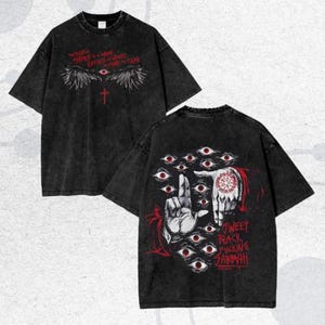 以下が含まれることがあります： 黒いグラフィックTシャツ2枚。1枚は前面に赤い十字架、目、テキストが描かれています。もう1枚は背面に手のジェスチャー、複数の目、テキストが描かれています。シャツはヴィンテージ感のある、使い古したような外観です。