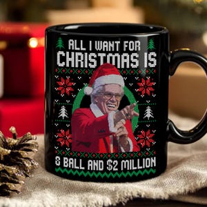 Pode incluir: Caneca de cerâmica preta com um design de camisola de Natal. A caneca apresenta o texto "ALL I WANT FOR CHRISTMAS IS 8 BALL AND $2 MILLION" com uma imagem de um homem com um chapéu de Papai Noel e um terno vermelho.