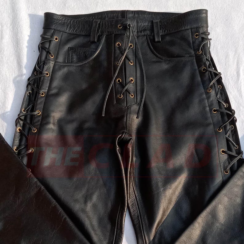 May include: Black leather pants with a lace-up detail on the sides. The laces are tied with a knot at the top of the pants.