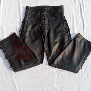 May include: Black leather pants with lace-up detailing on the sides. The pants have a classic five-pocket design and a relaxed fit.