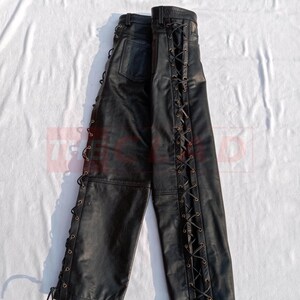 May include: Black leather pants with lace-up detailing on the sides. The laces are brown and the pants have a relaxed fit.