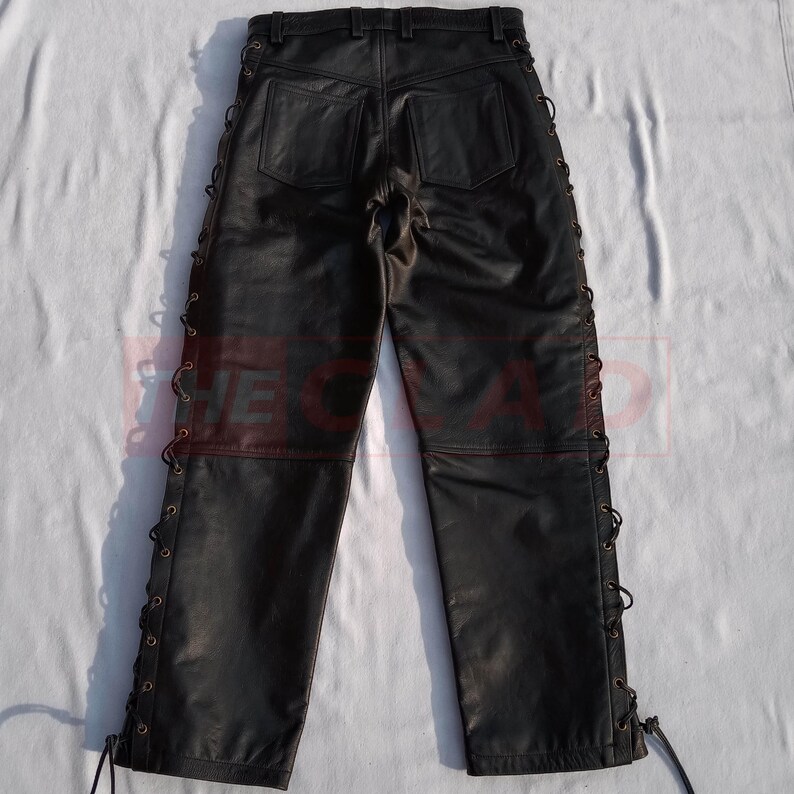 May include: Black leather pants with lace-up detailing on the sides. The pants have a classic five-pocket design and a straight leg.
