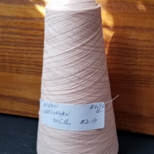 May include: A cone of pale pink nylon thread with a label that reads "Nylon/Lycra 300 yds $5.13 $6.95"