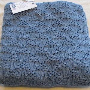 May include: A blue knitted baby blanket with a diamond pattern. The blanket is made of soft yarn and is perfect for cuddling.