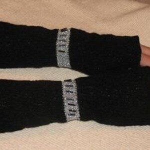 Könnte beinhalten: Schwarze Fingerlose Strickhandschuhe mit silbernem und schwarzem Perlenbesatz.