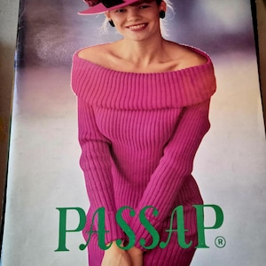 May include: A woman wearing a magenta off-the-shoulder sweater dress and a matching hat with a black ribbon and a flower accent. The word "PASSAP" is printed in green, along with text in German, French, and English.