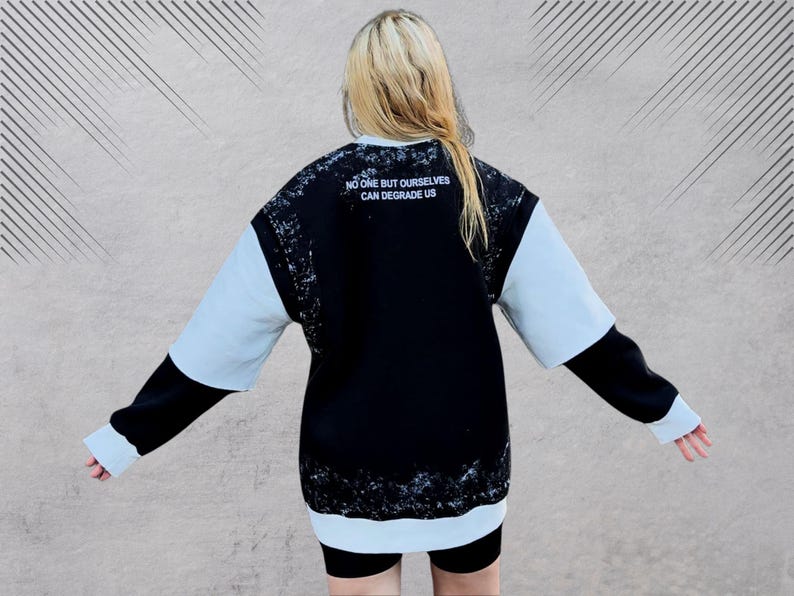 May include: Black and light blue sweatshirt with a white graphic print that says "No one but ourselves can degrade us".