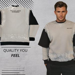 May include: A gray sweatshirt with black sleeves and a white splatter pattern. The front of the sweatshirt has the text "NO LIMIT BUT OURSELVES CAN DEGRADE US" printed on the top and "DON'T GIVE UP" printed on the bottom.