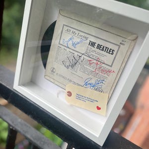 May include: A framed The Beatles All My Loving EP record sleeve featuring signatures from the band members. A small cream-colored tag is attached to the frame with the printed text: And in the end, the love you take is equal to the love you make.