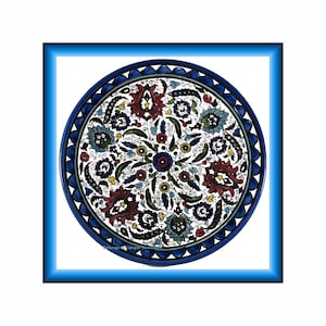 Puede incluir: Un plato redondo de cerámica decorativo con un diseño floral detallado en rojo, azul y amarillo sobre un fondo blanco. El plato tiene un borde azul oscuro con un borde festoneado y está enmarcado por un borde azul.