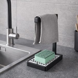 May include: A black kitchen sponge holder with a gray microfiber cloth hanging from a black bar. A green and white sponge sits on the holder's tray. The holder is on a gray countertop near a stainless steel sink.