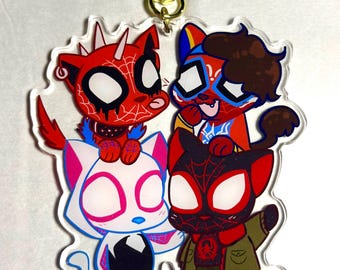 May include: A set of four acrylic charms featuring cartoon cats dressed as Spider-Man characters. The charms are red, black, white, and blue. The charms are attached to a gold key chain.