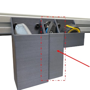 May include: Gray 3D-printed tool organizer with three compartments. Each compartment holds a different tool, including a tape measure, a utility knife, and a small object. The organizer is mounted on a silver rail.