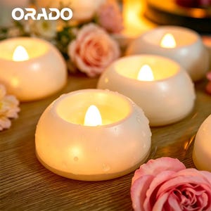 May include: Cream-colored, battery-operated LED candles with a soft, warm glow. The candles are round and have a realistic flame effect. The image also includes pink roses and the word "ORADO" in white letters.