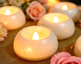 May include: Cream-colored, battery-operated LED candles with a soft, warm glow. The candles are round and have a realistic flame effect. The image also includes pink roses and the word "ORADO" in white letters.