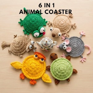 May include: A set of six handmade crochet animal coasters, featuring a frog, mouse, turtle, and bird. The coasters are in green, yellow, brown, and grey. A small floral teapot is also present. The text "6 IN 1 ANIMAL COASTER" is at the top.
