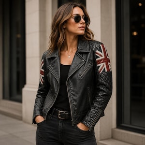 May include: Black leather jacket with a Union Jack flag design on the sleeves. The jacket has a classic biker style with a notched collar, zipper pockets, and a quilted shoulder detail. The model is wearing sunglasses and a black top.