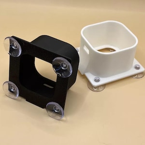 May include: Two square-shaped suction cup mounts, one black and one white. Both mounts have a square opening in the centre.