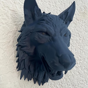 May include: A dark blue wolf head wall sculpture with detailed fur and an open mouth, mounted on a textured white wall. The sculpture features pointed ears and a fierce expression, showcasing a realistic design.
