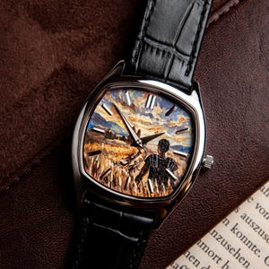 May include: A wristwatch with a silver-toned cushion-shaped case and a black embossed leather strap. The watch face features a detailed impressionistic painting of a person standing in a golden wheat field under a cloudy sky, with silver markers.
