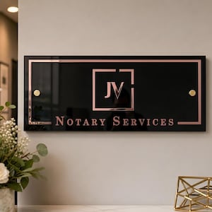 May include: A rectangular black sign with a glossy finish featuring a rose gold border and rose gold lettering that reads JV and NOTARY SERVICES. The sign is mounted with two circular rose gold hardware accents on the left and right sides.