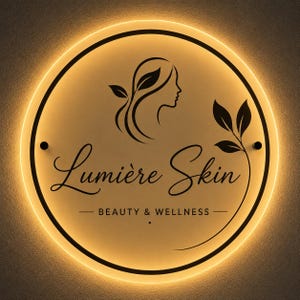 May include: A circular wall sign with a warm golden backlight. The sign features a black line-art profile of a face with leaves, the text Lumière Skin in a cursive font, and the text BEAUTY & WELLNESS in a sans-serif font with two small dots.