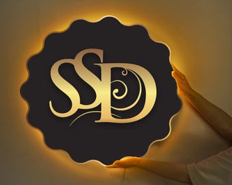 May include: A black sign with a gold "SPD" logo and a decorative swirl design. The sign is illuminated with warm white LED lights.
