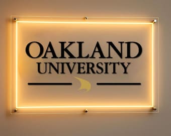 May include: A rectangular sign with the words "OAKLAND UNIVERSITY" in black, with a yellow and black logo. The sign has a glowing yellow border and is mounted with small, gold-colored fasteners.