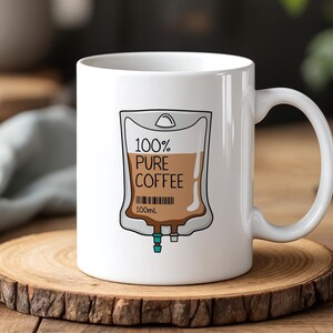 Puede incluir: Taza de café de cerámica blanca con un gráfico de una bolsa IV llena de líquido marrón y el texto "100% PURE COFFEE 100mL".