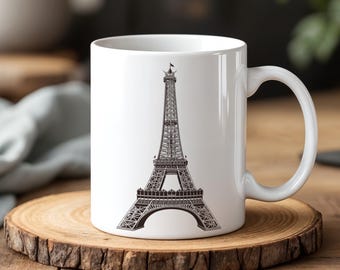 May include: White ceramic mug with a black and white illustration of the Eiffel Tower on the front. The mug has a handle on the right side.