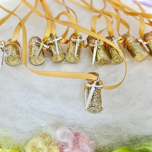 May include: A set of gold glitter filled vials with silver sword charms on gold ribbon necklaces.