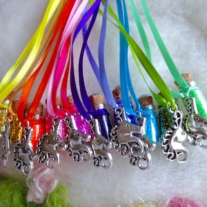 May include: A selection of miniature glass bottles filled with coloured glitter, each sealed with a cork. They hang from satin ribbons in rainbow hues. Silver unicorn charms are attached to the ribbons.