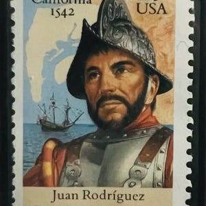 May include: A postage stamp featuring Juan Rodríguez Cabrillo, the Explorer of California, from 1542. The stamp has a portrait of Cabrillo in armor and a helmet, with a ship in the background. The stamp is valued at 29 cents.