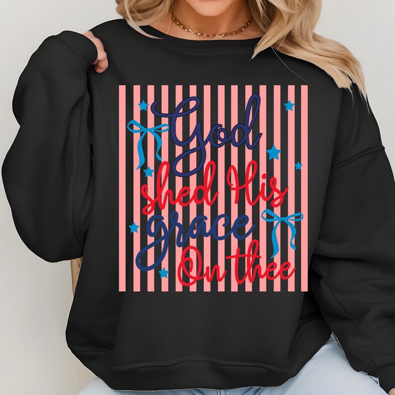 May include: Black sweatshirt with a vertical striped design in pink and white. The text "God Shed His Grace On Thee" is in blue and red script, with blue bows and stars.