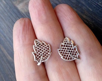May include: A pair of silver leaf-shaped earrings with a delicate, openwork design.