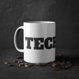 Könnte beinhalten: Weiße Keramik-Kaffeetasse mit dem Wort "TECH" in schwarzen Fettdruck.