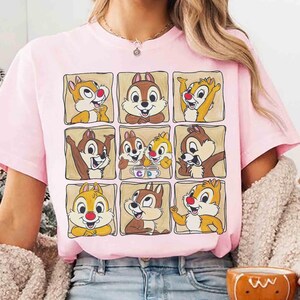 May include: A light pink t-shirt featuring a grid of nine cartoon images of Chip and Dale. Each image is framed in a light brown square. The characters are in various poses, with different expressions.
