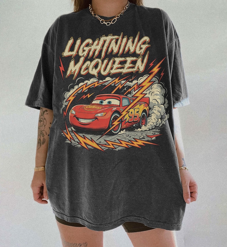 May include: Dark gray t-shirt featuring Lightning McQueen from the Cars movie. The graphic shows the red race car with the number 95, surrounded by lightning bolts and the text "Lightning McQueen".