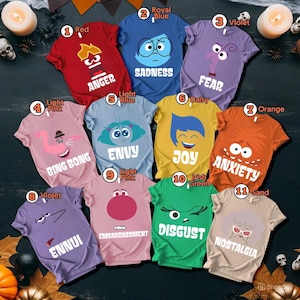 May include: A collection of eleven colorful t-shirts, each featuring a different emotion from the movie Inside Out. The shirts are in various colors, including red, blue, yellow, and green, with character graphics and emotion names.