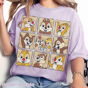 May include: Orchid-colored t-shirt featuring a grid of cartoon chipmunks in various poses. The chipmunks are in brown and yellow with red noses. The shirt has a relaxed fit and is made of soft material. The text "Color: Orchid" is at the bottom.