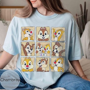May include: Light blue t-shirt featuring a grid of nine cartoon chipmunk illustrations in individual tan squares. The chipmunks have brown and yellow fur, red noses, and various expressions. The word "Chambray" is printed at the bottom left.