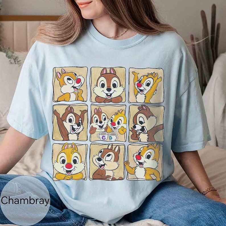 May include: Light blue t-shirt featuring a grid of nine cartoon chipmunk illustrations in individual tan squares. The chipmunks have brown and yellow fur, red noses, and various expressions. The word "Chambray" is printed at the bottom left.