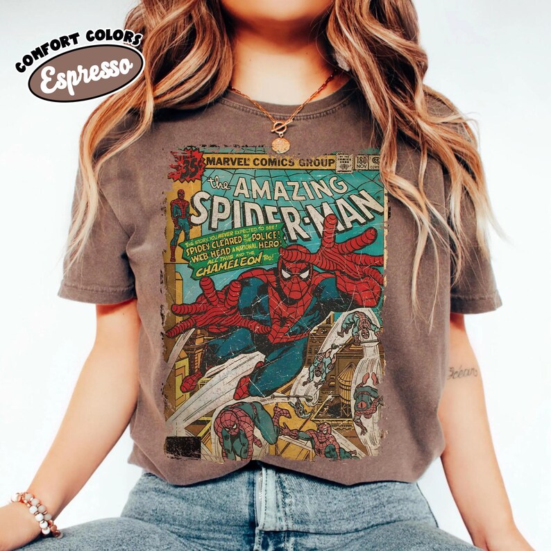 Puede incluir: Una camiseta de manga corta de color marr&oacute;n oscuro con un gr&aacute;fico de estilo vintage de la portada de un c&oacute;mic de Marvel, The Amazing Spider-Man. El estampado muestra a Spider-Man en una pose din&aacute;mica con colores rojo y azul.