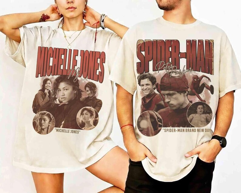 May include: Two cream-colored t-shirts featuring movie-themed graphics. One shirt displays "MICHELLE JONES" in red lettering with images of the actress. The other shirt says "SPIDER-MAN" with images of the actor.