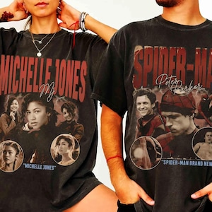 May include: Two dark gray t-shirts featuring movie-themed graphics. One shirt displays "MICHELLE JONES" in red lettering with images of a woman. The other shirt says "SPIDER-MAN Peter Parker" with images of a man.