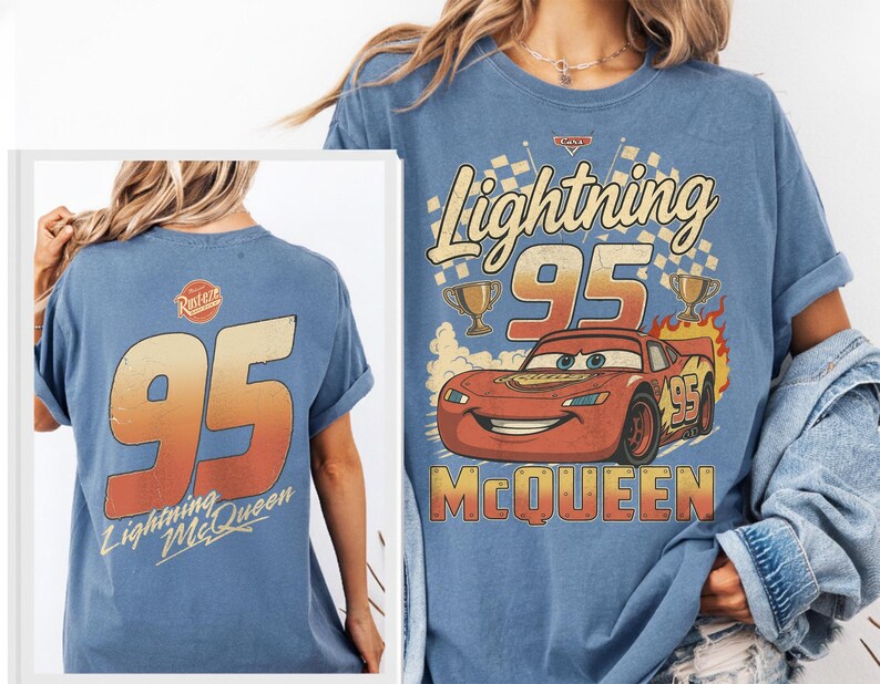 May include: A blue t-shirt featuring a graphic of the character Lightning McQueen with the text Lightning 95 McQueen and trophies. The back of the shirt displays the number 95 in a gradient orange font with the text Lightning McQueen below it.