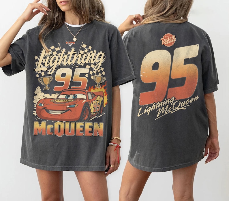 May include: A charcoal gray oversized t-shirt featuring a graphic of the red race car Lightning McQueen with the number 95, checkered flags, and trophies on the front, and a large 95 with the text Lightning McQueen on the back.