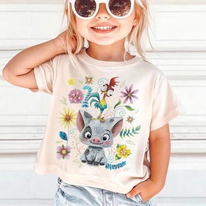 K&ouml;nnte beinhalten: Hellbeige T-Shirt mit einem Cartoon-Schwein und Hahn-Design, umgeben von bunten Blumen und Bl&auml;ttern. Das Design ist auf dem T-Shirt zentriert und wirkt l&auml;ssig. Getragen von einem kleinen Kind.